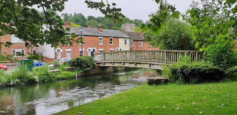 A row of terraced houses next to a river with a bridge over it in Winchester