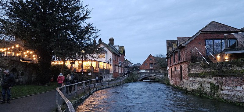 A restaurant lit up in the evening next to a river in Winchester