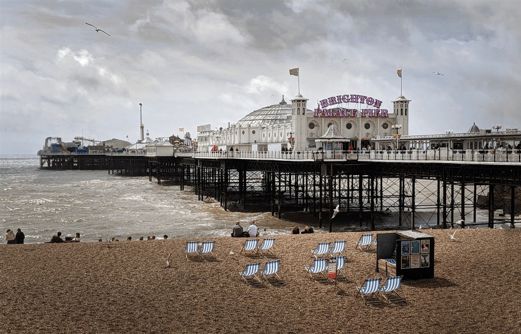 A beach in the foreground with a pier stretching away into the sea in Brighton.