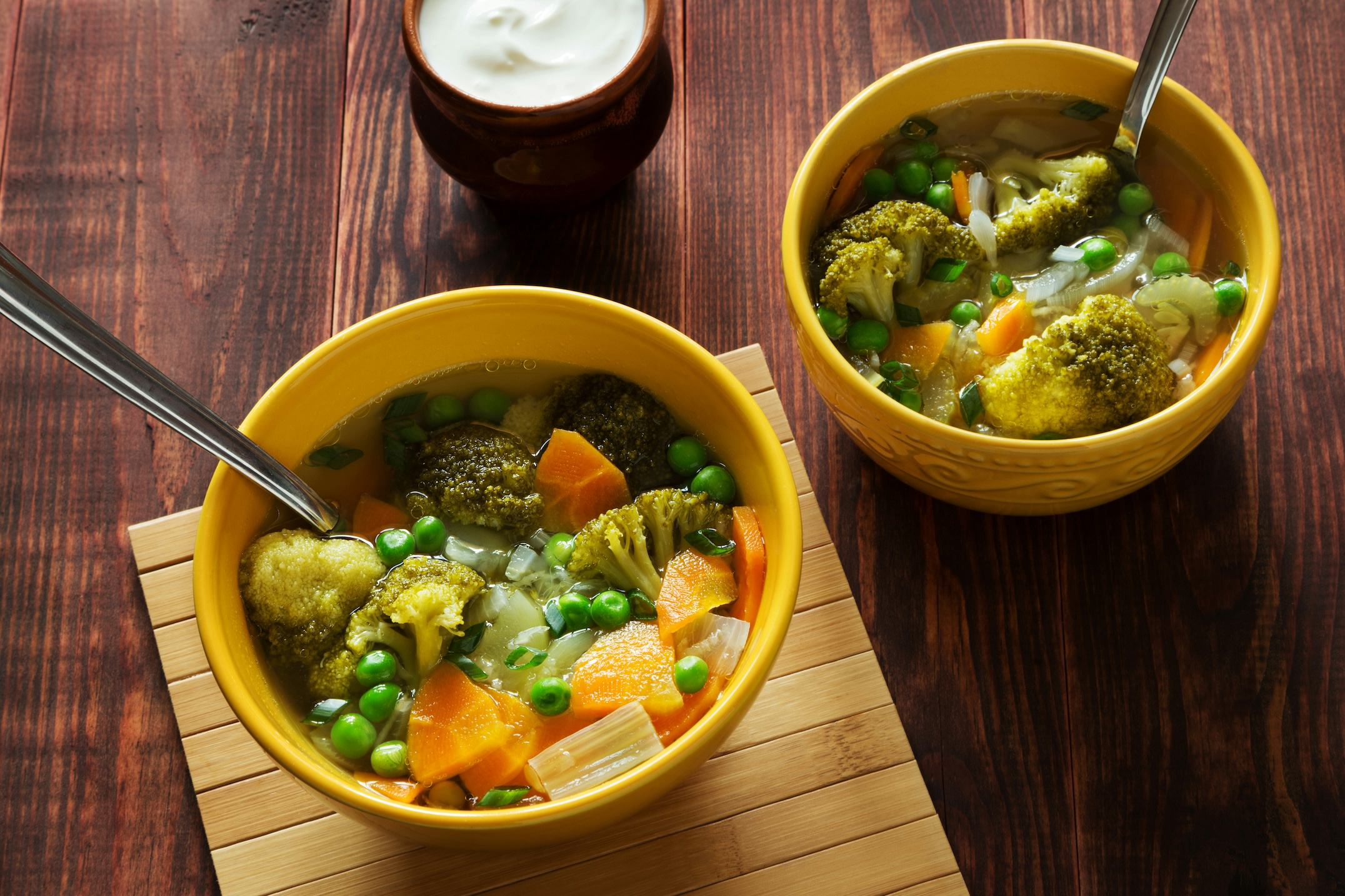Two bowls filled with a vegetable soup with broccoli and carrots.