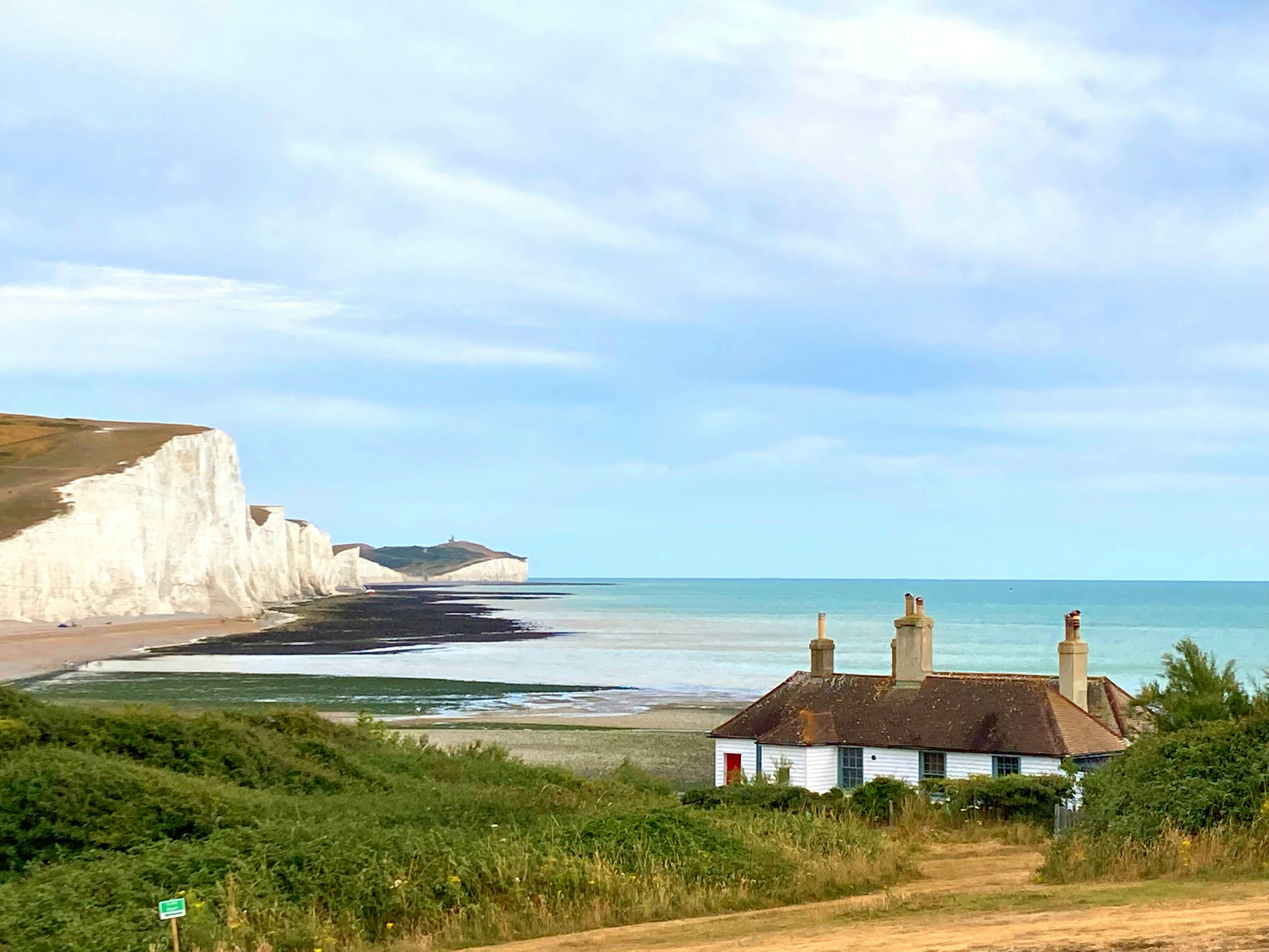 A cottage in the foreground and white cliffs behind.