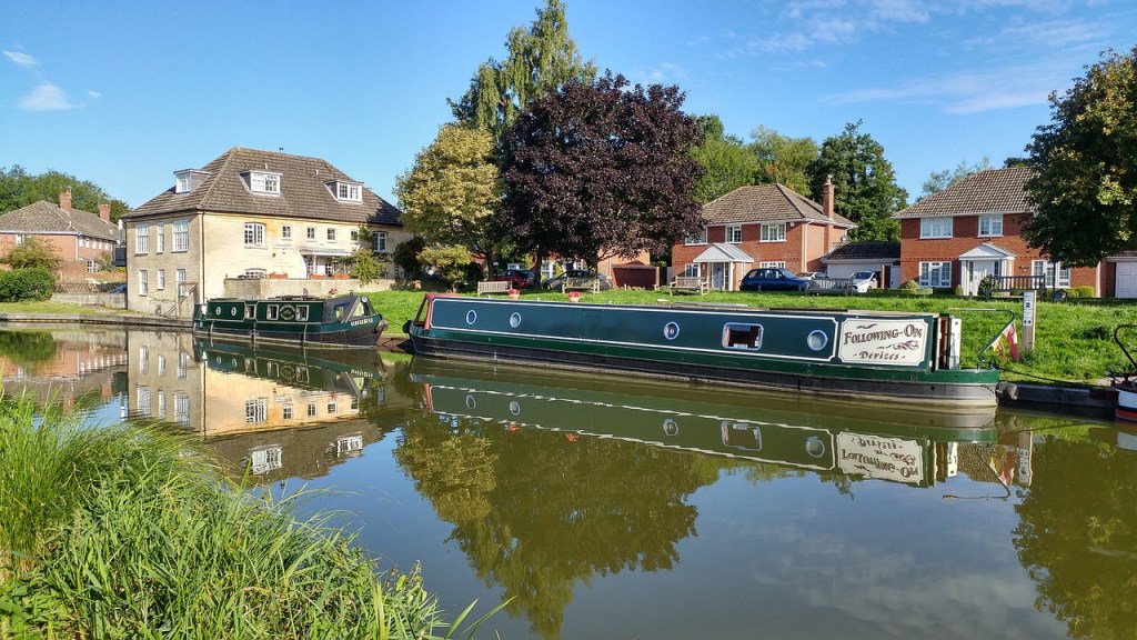 A canal boat with houses behind.