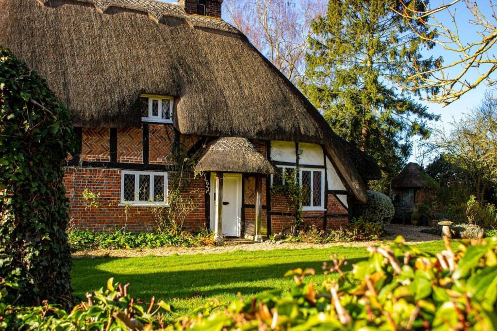 A chocolate box English cottage with a thatched roof.