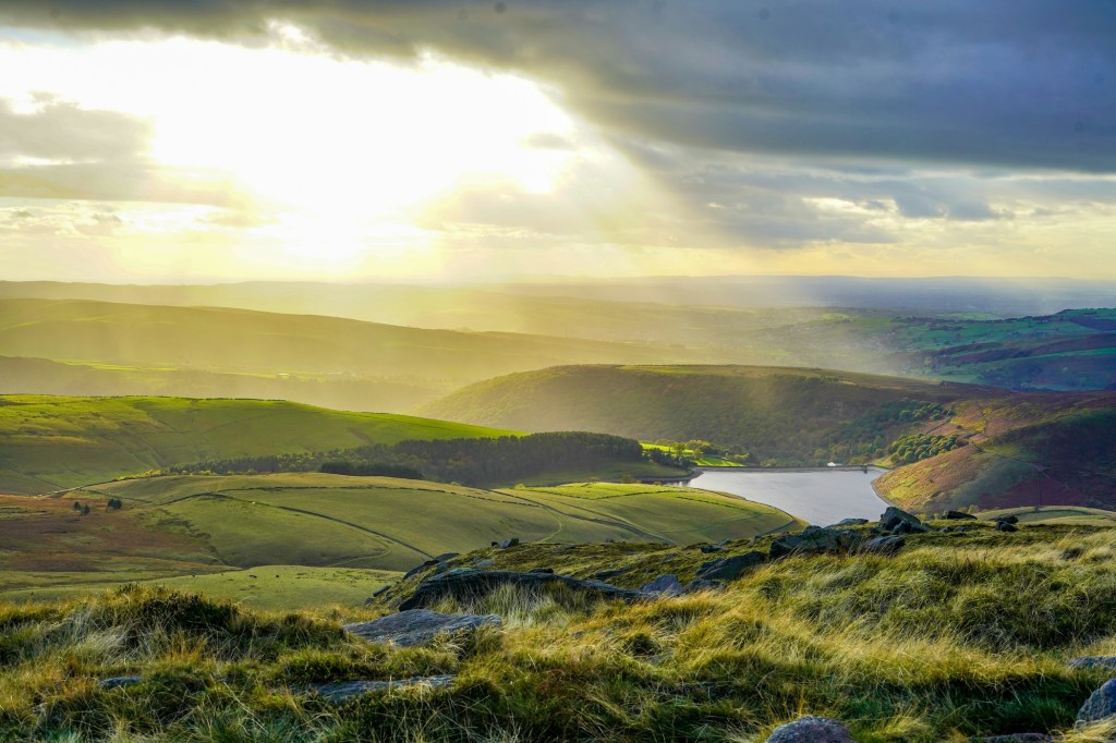 A view across the fields and rocky hilltops of the Peak District.