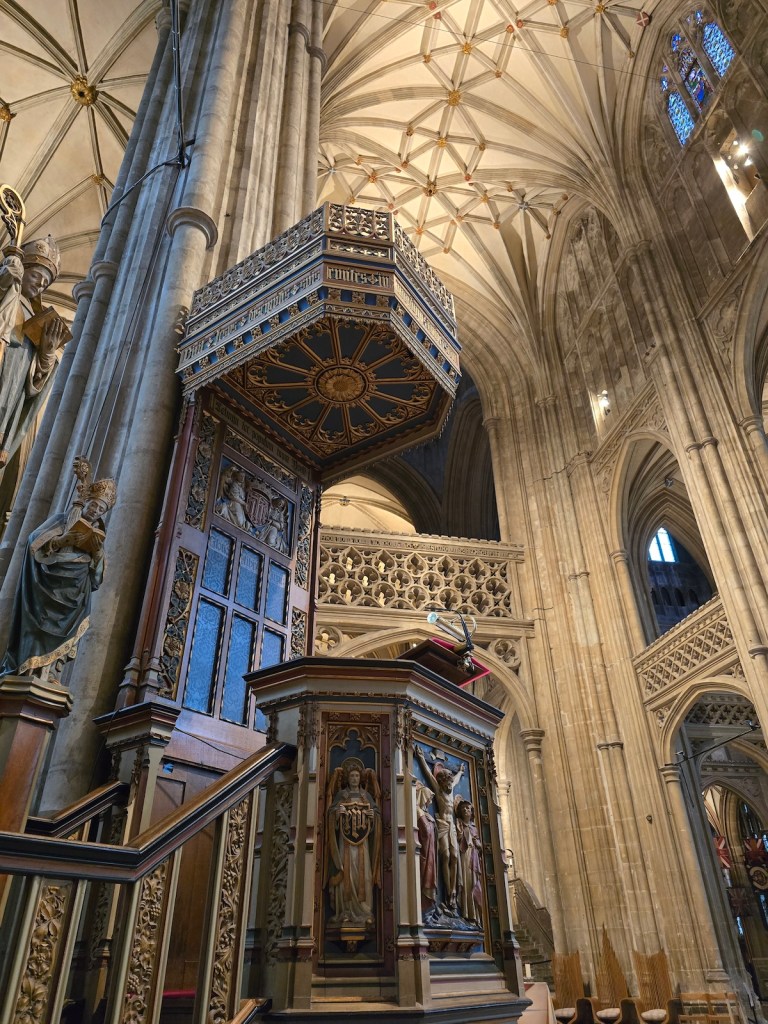 An interior shot of Canterbury Cathedral showing the intricate stone carving and the pulpit.