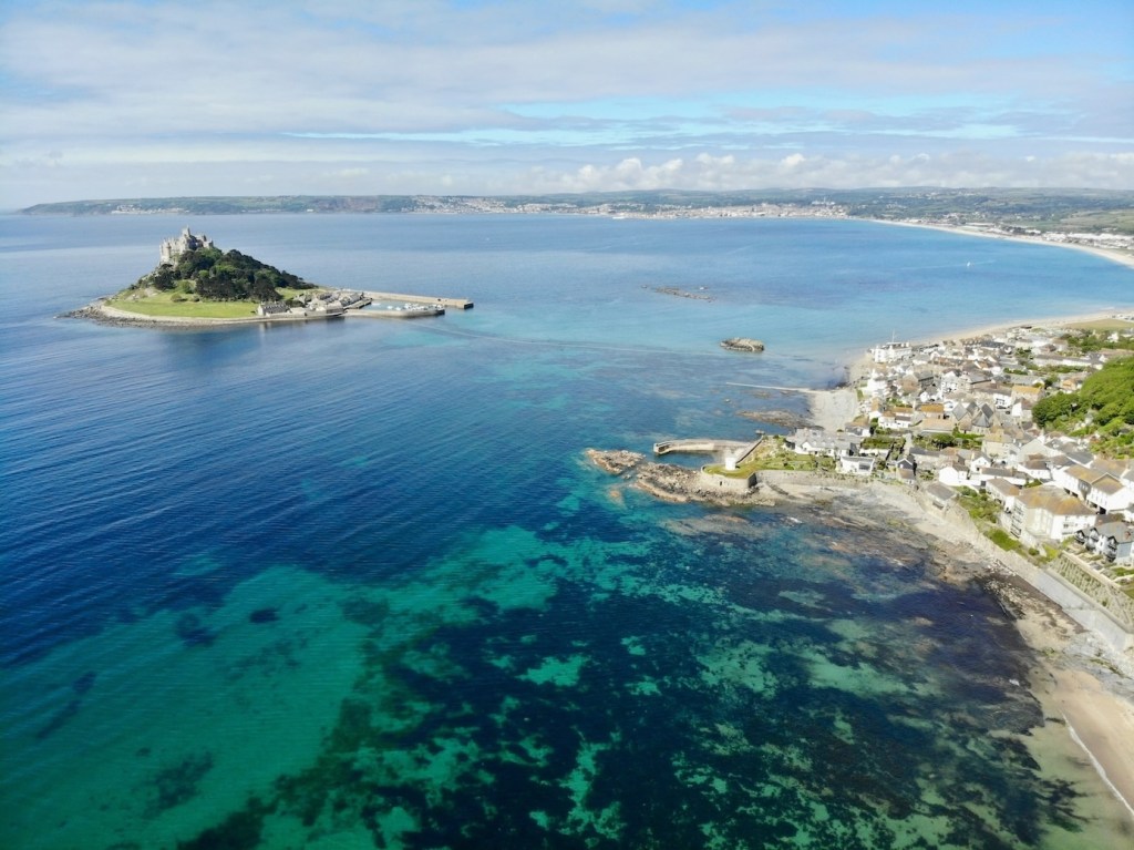 An aerial view of the Cornish coast with St Michael's Mount a little way into the water. 