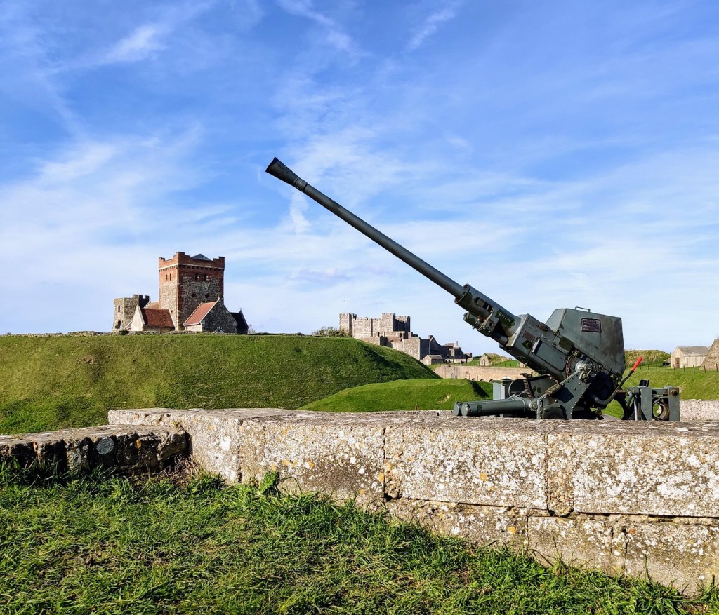 A view of Dover Castle on raised ground with a World War Two gun in the foreground.