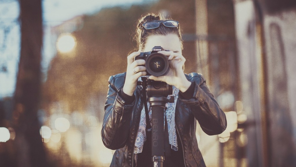 A woman taking a photograph looking toward the camera.