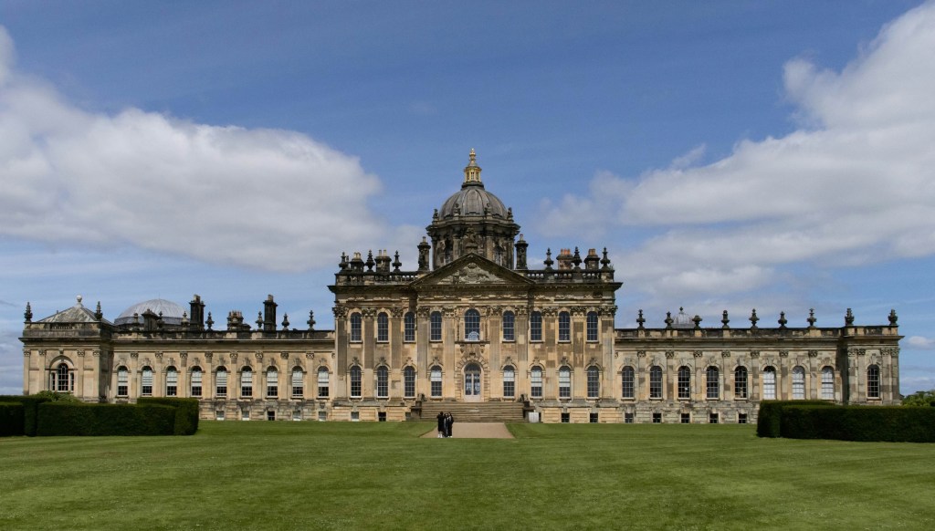 The frontage of Castle Howard, a wide stately home with a dome in the centre.