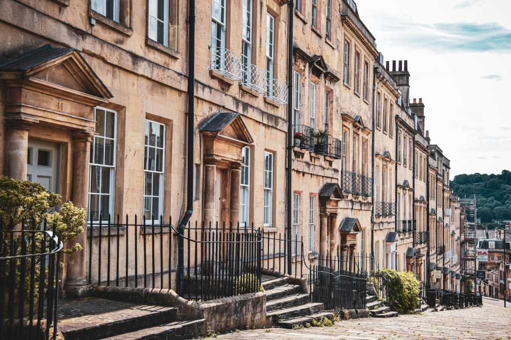 A row of terraced buildings in Bath. They're several storeys tall and made of golden-coloured stone.