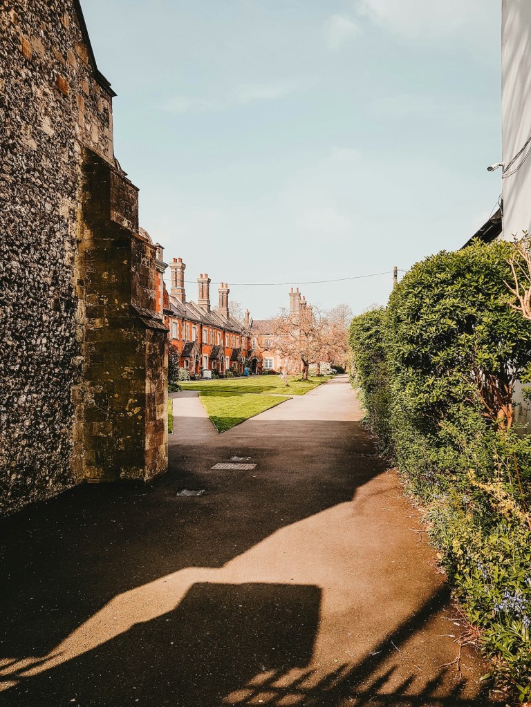 Looking through a gateway into a historic square of buildings in Winchester.