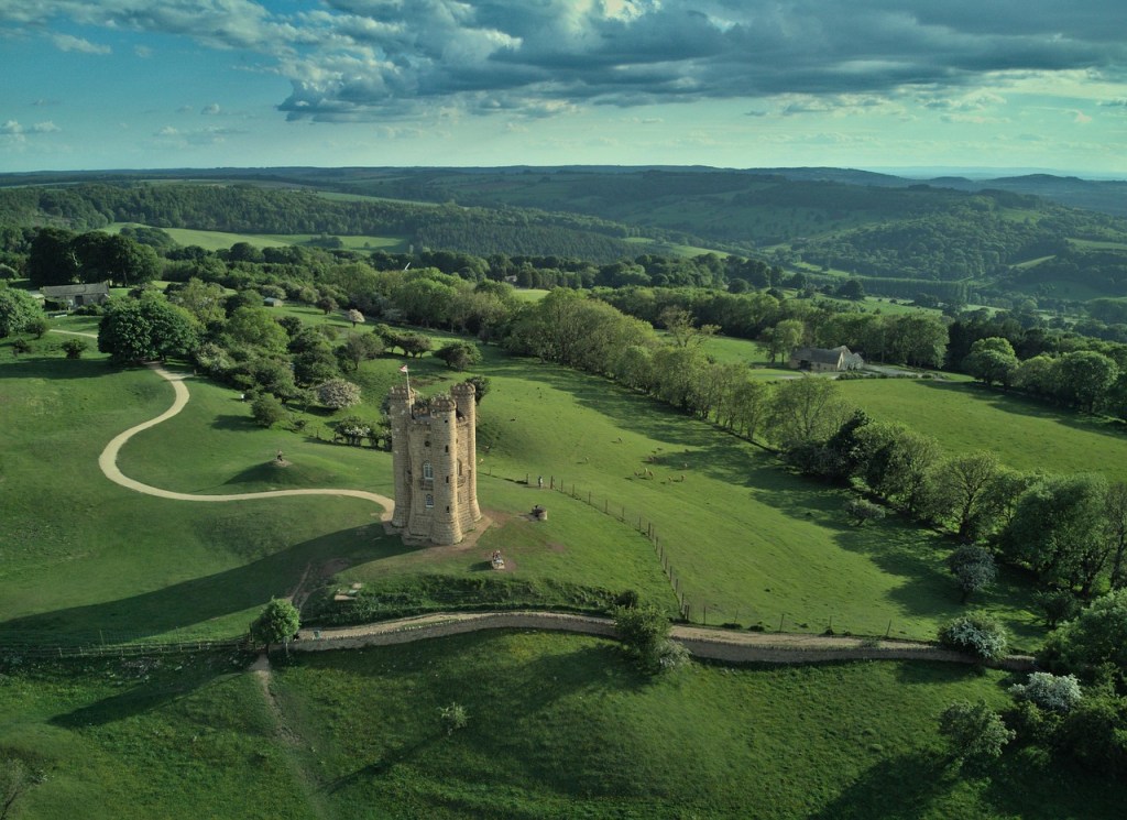 Aerial view of Broadway Tower, a stone tower overlooking rolling green countryside.
