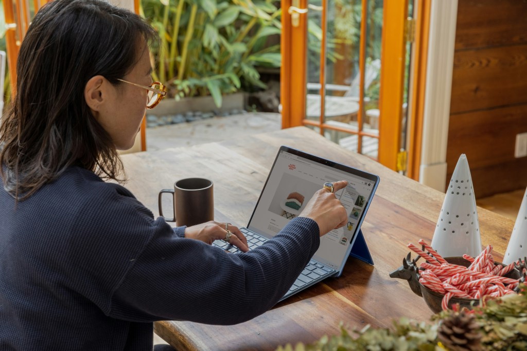 A woman works on her laptop at home with a cup of tea next to her.