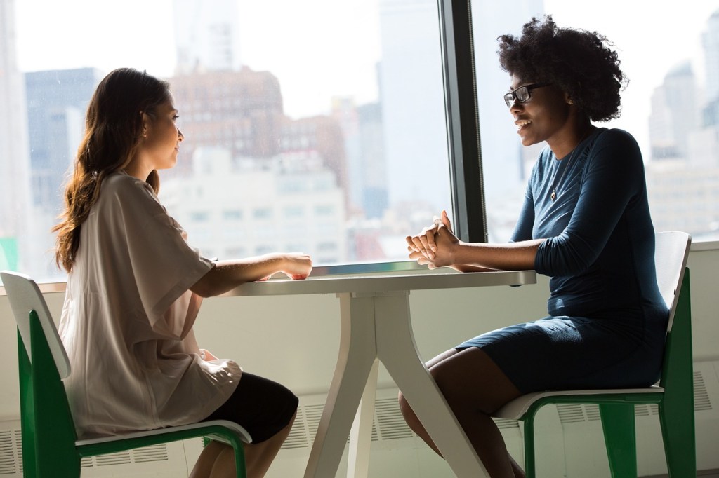 Two women sitting at a table talking.