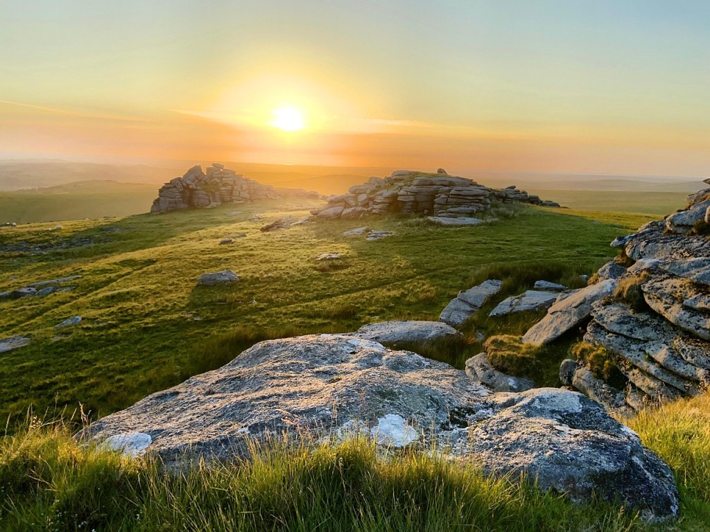 Sunset over Dartmoor with rocky and grassy mounds. 