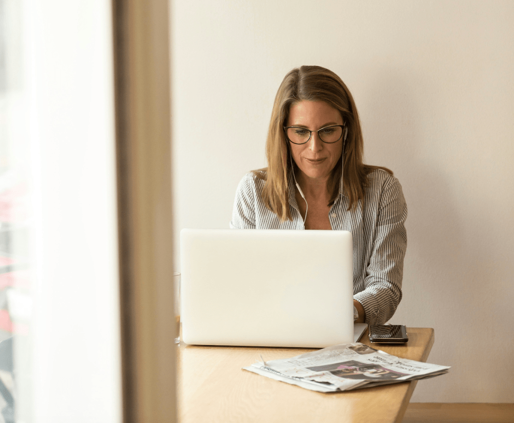 A woman sits alone working on her laptop. 