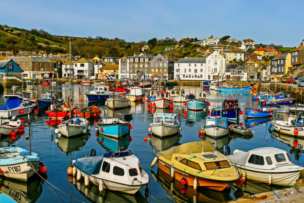 A colourful harbour in Cornwall. Fishing boats in the harbour and buildings lining the dockside.